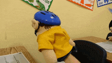 a puppet wearing a helmet sits at a desk