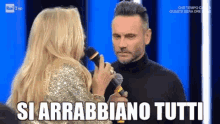 a woman is holding a microphone next to a man with the words si arrabbiano tutti written on the screen