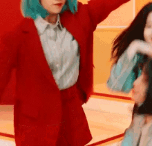a woman with blue hair is wearing a red suit and a blue shirt .