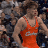 a wrestler in an orange cowboys uniform is standing in front of a crowd