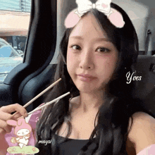a woman is sitting in the back seat of a car eating food with chopsticks .