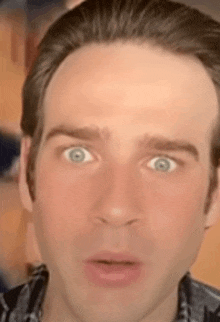 a man with blue eyes is making a surprised face .