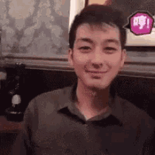 a man is smiling and looking at the camera while sitting at a table in a restaurant .