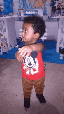 a little boy wearing a red mickey mouse shirt