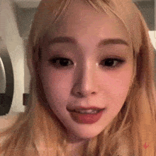 a close up of a woman 's face with blonde hair and a red lip .