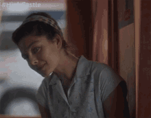 a woman wearing a headband and a white shirt is standing in front of a sign that says high castle