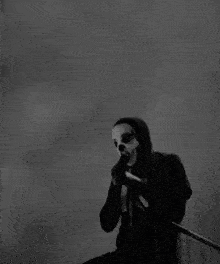a black and white photo of a man in a mask holding a microphone .