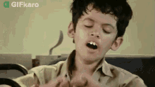 a young boy is making a funny face with his mouth open while sitting in a chair .