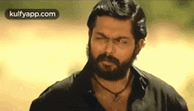 a man with a beard is making a funny face while smoking a cigarette .