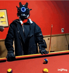 a man wearing a helmet stands on a pool table with pool balls