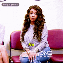 a woman is sitting in a waiting room with the word no on her shirt .