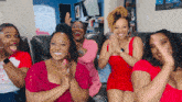 a group of women sitting on a couch clapping and laughing