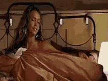 a woman is laying in bed with a man sleeping next to her and using a laptop .