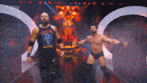two wrestlers are standing on a stage with a skull in the background .