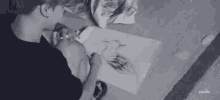 a man is sitting at a table drawing a picture with a pencil .