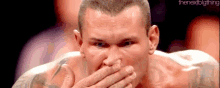 a close up of a man covering his mouth with his hand .