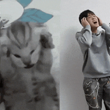 a person covering their ears with their hands while standing next to a cat