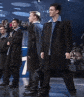 a group of men are standing in a line holding microphones