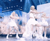 a group of women are dancing on a stage wearing white dresses and boots .