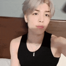 a young man wearing a black tank top and a necklace