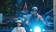 a man and a woman are riding a motorcycle with a flag on top