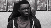 a black and white photo of a man wearing glasses and a grey shirt