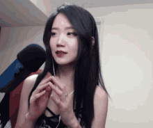 a woman with long black hair is wearing earbuds and a ring