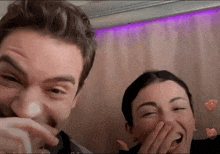 a man and a woman are laughing and covering their faces