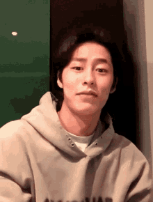 a young man wearing a grey hoodie with the word a on it