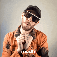 a man wearing sunglasses and a hat has the word mcdh on the bottom