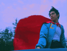 a man wearing a blue jacket and a red cape has the letter l on his jacket