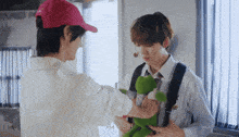 a man in a pink hat holds a stuffed frog