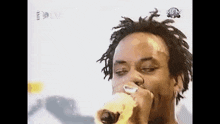 a man with dreadlocks is singing into a microphone on a stage .