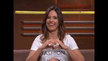 a woman wearing a fashion t-shirt making a heart with her hands