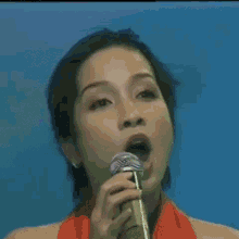 a woman singing into a microphone with a red scarf around her neck