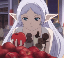 a girl with white hair is holding a red apple in front of a pile of red apples