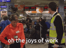 a woman in an orange shirt is standing next to a man in a yellow vest with the words oh the joys of work written below her