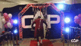 a man is walking on a red carpet in front of a large sign that says cap