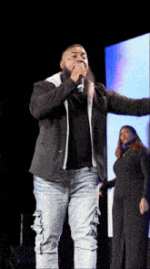 a man with a beard is singing into a microphone on a stage