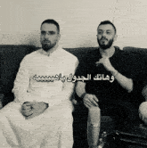 two men sitting on a couch with arabic writing on their faces