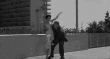a bride and groom are dancing on a bridge .