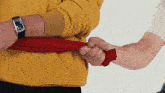 a man wearing a square watch is holding a red cloth