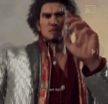 a man with curly hair is talking on a cell phone and says `` give em hell '' .