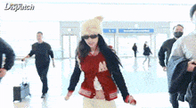 a woman wearing a hat and sunglasses is dancing in an airport