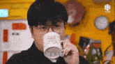 a man wearing glasses is drinking from a mug that has a bear on it