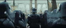 a group of soldiers are standing in a line and one of them has a shield on his back