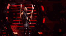 a wrestler is holding two sticks in the air while wearing a black tank top with a tiger on it