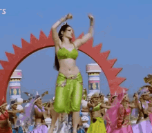 a woman in a green outfit is dancing in front of a crowd of people .