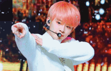 a young man with pink hair is wearing a white sweater and earphones