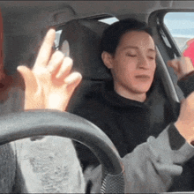 a person sitting in a car with their eyes closed giving the middle finger